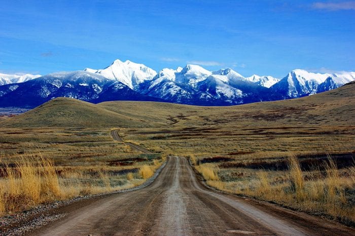 Photo of long dirt road leading to mountains in Montana